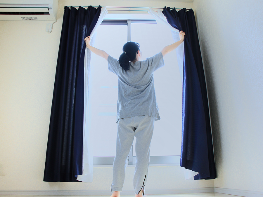 朝カーテンを開ける女性