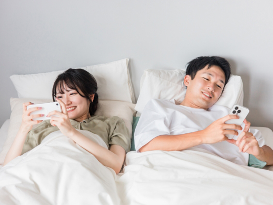 ベッドでスマホを触る男性と女性
