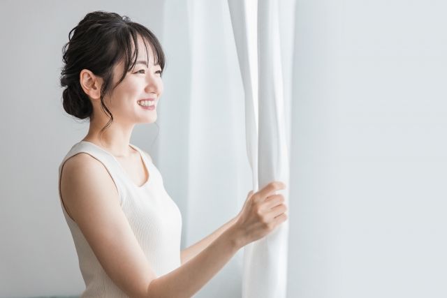 カーテンを開ける女性