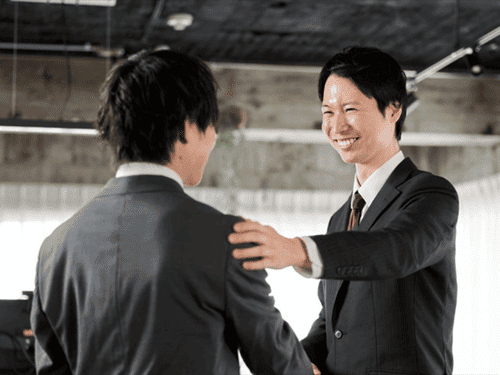 部下の方をたたいて称賛する男性上司